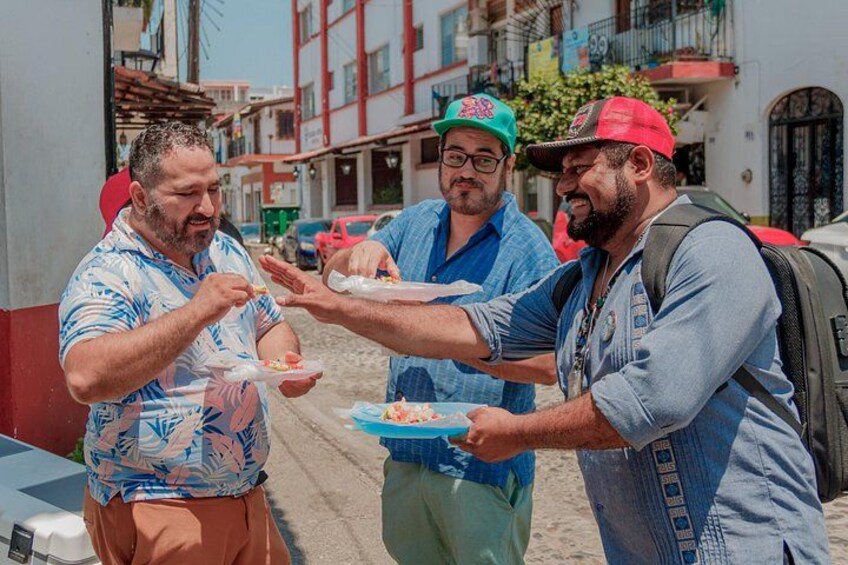 Three men sharing food on a street. 1