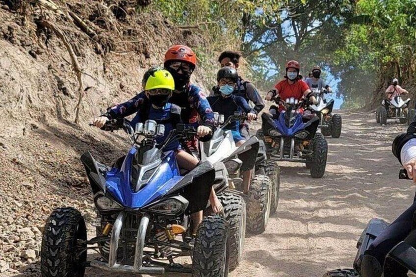 Personas manejando cuatrimotos por un sendero de tierra rodeado de árboles. 2