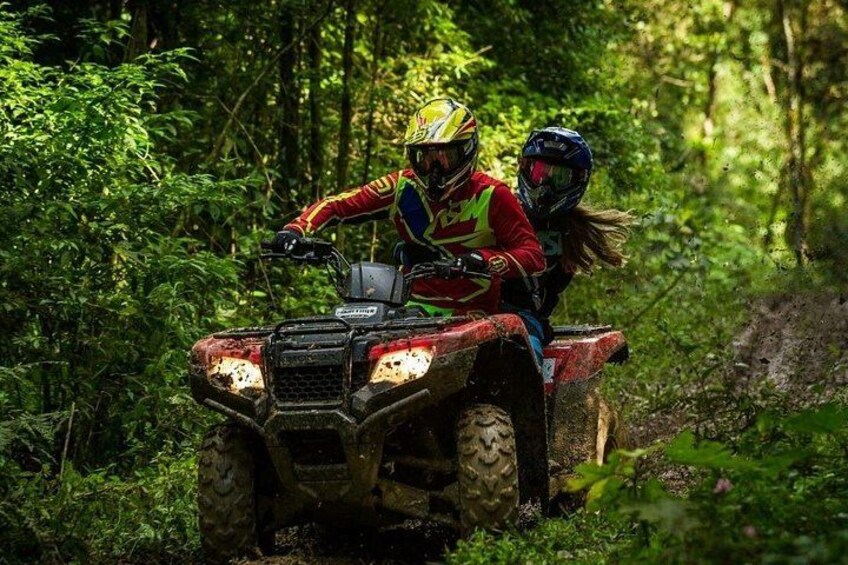 Dos personas paseando en un cuatrimoto por un área boscosa. 3