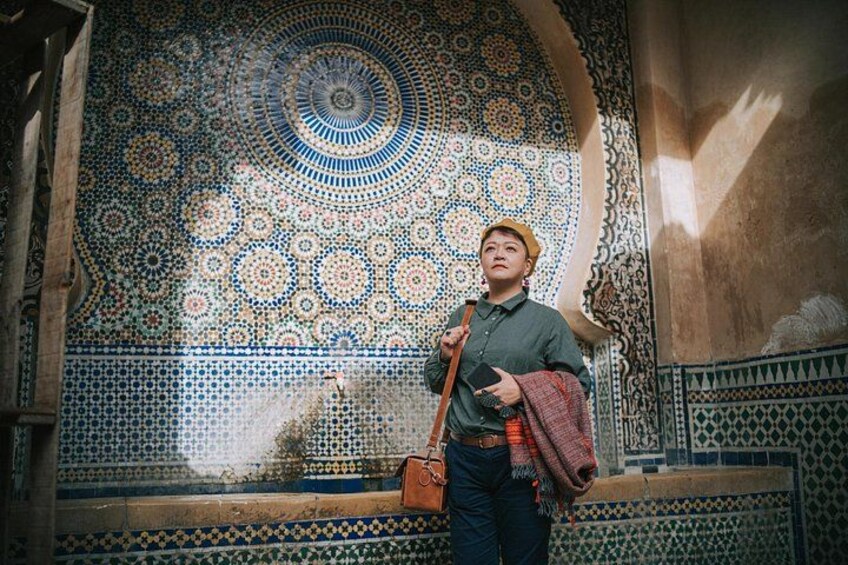 A person standing in front of a detailed mosaic wall. 4