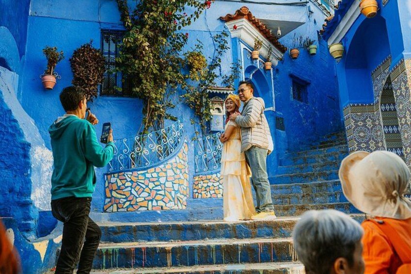 A person taking a photo of a couple on a blue-painted staircase. 2