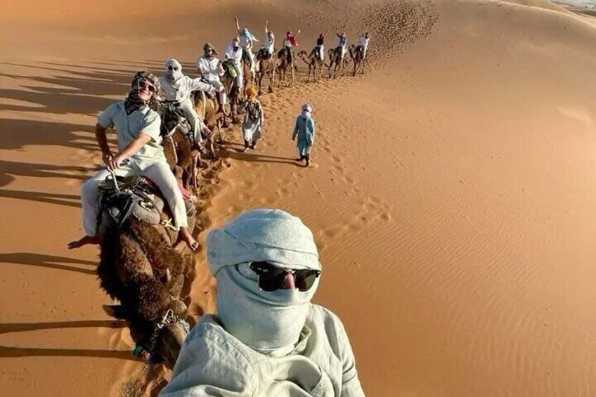 A group of people riding camels through a desert. 2