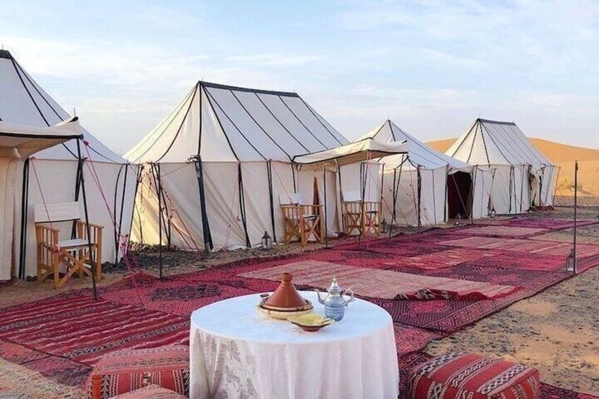 A desert campsite with tents and a round table with a pot. 4