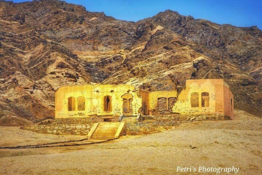 An ancient ruin with arches and a staircase, set against a mountainous backdrop. 3