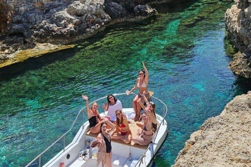 A group of people on a boat in a clear, narrow waterway surrounded by rocky cliffs. 1