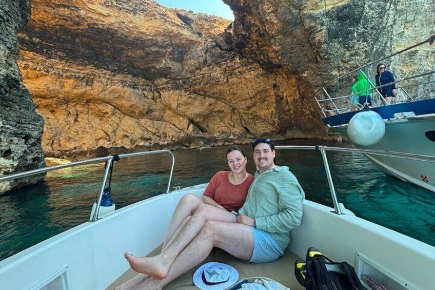 Two people on a boat in a rocky cove with clear water. 3