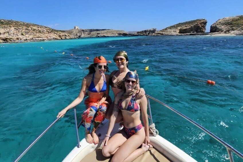 Two people on a boat in a turquoise sea with rocky cliffs in the background. 2