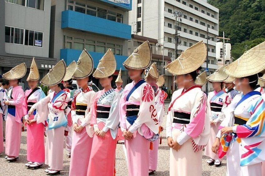 A group of people in traditional Japanese attire with conical hats, standing in a line. 2