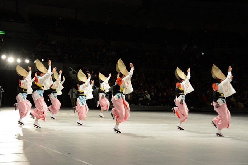 A group of dancers performing on a stage with a spotlight. 2