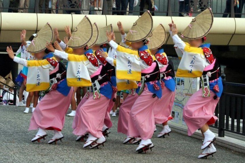 A group of performers in traditional attire with fans, performing a dance. 4