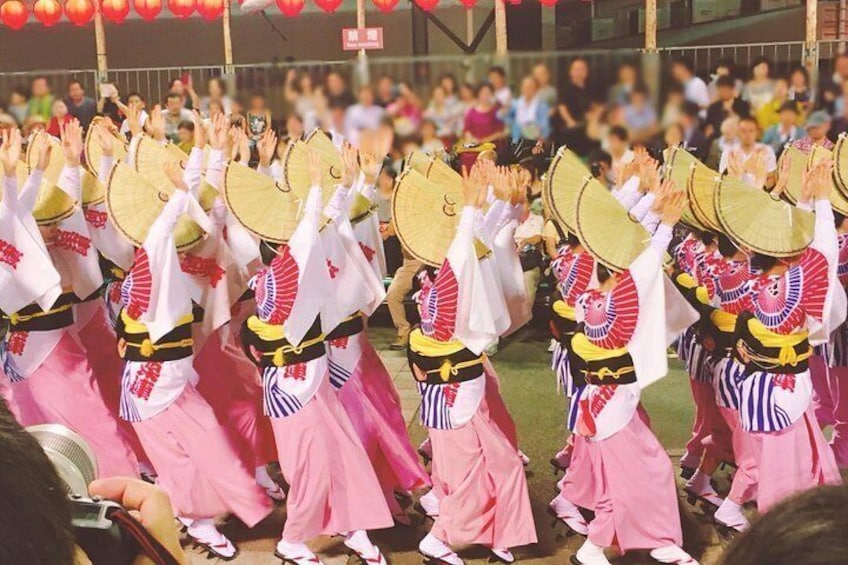 A group of performers in traditional costumes with fans, performing in front of an audience. 5