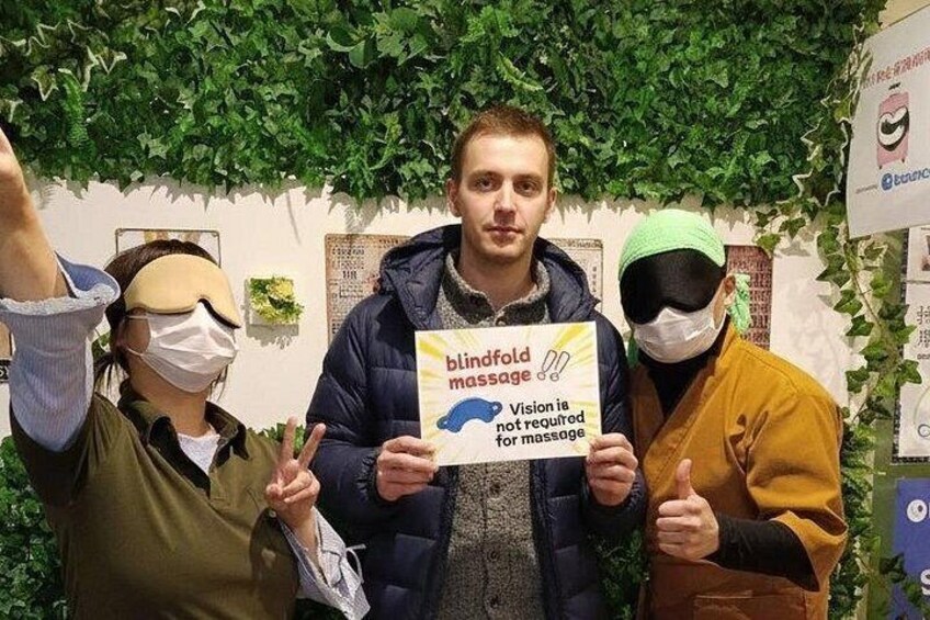 Drei Personen halten ein Schild, auf dem 'Blindmassagen' steht. 2
