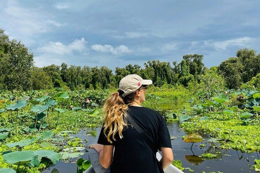 A person standing by a pond surrounded by lily pads and greenery. 4