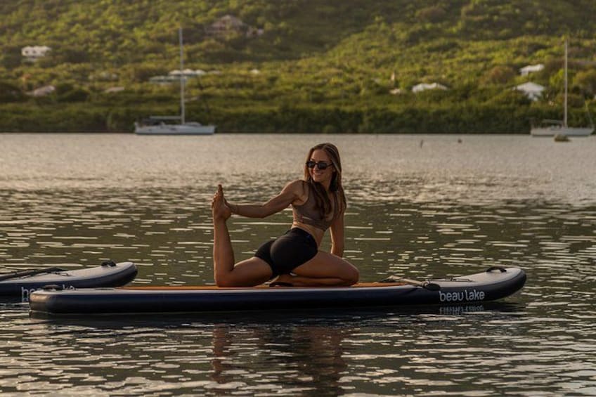 A person sitting on a paddleboard in a body of water with boats in the background. 5