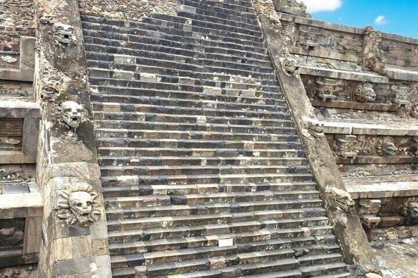 A weathered stone staircase with intricate carvings and steps leading up to a higher level. 2