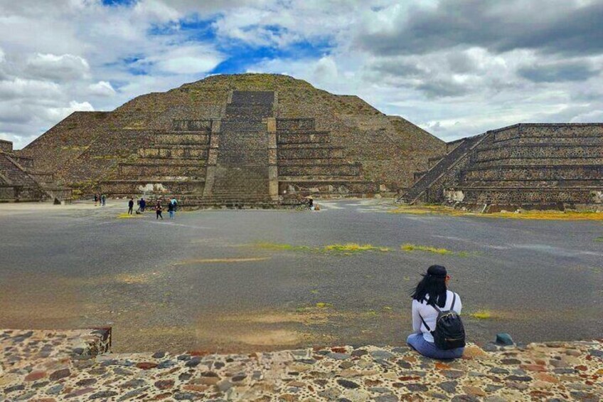 A large pyramid structure with a flat top, surrounded by a paved area with people walking. 5