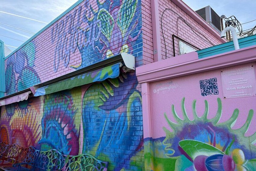 A colorful mural on a building with a pink facade and a QR code. 5