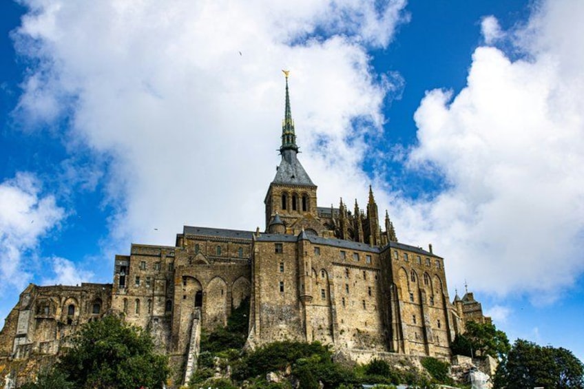 A large historic building with a prominent tower and spires, surrounded by greenery. 2