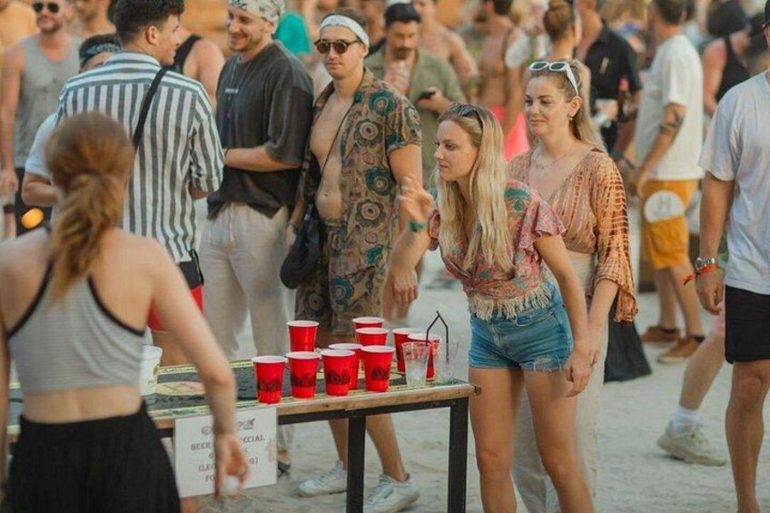A group of people at an outdoor event with a table displaying red cups and a sign that reads 'BEER SPECIAL.' 3
