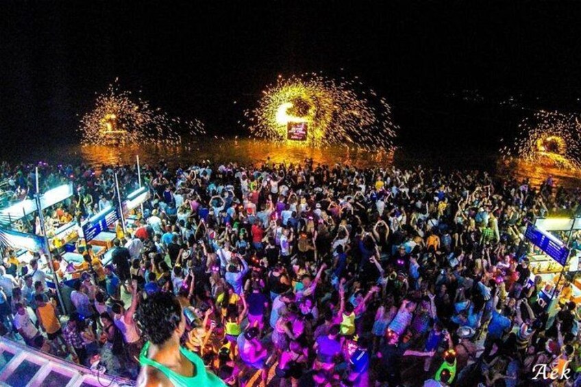 A crowded outdoor event with a stage and fireworks. 2