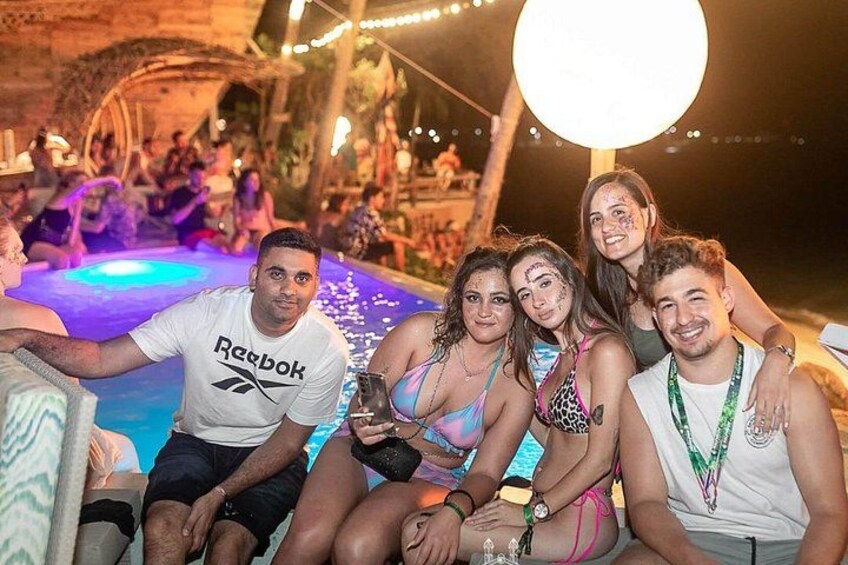 Un groupe de personnes est assis au bord d’une piscine, près d’une fontaine et d’un ensemble d’éclairages décoratifs. 5