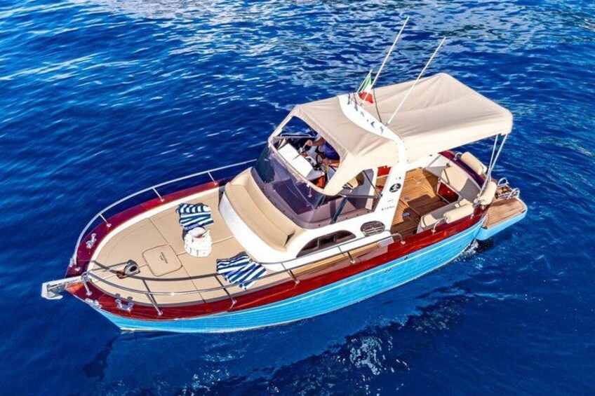 A small motorboat with a canopy, red and blue hull, and a wake behind it. 4