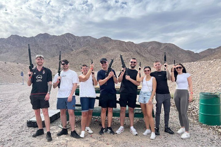 A group of people holding rifles in a desert landscape with mountains in the background. 5