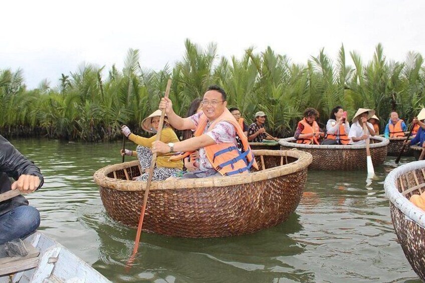 People in traditional boats on a river surrounded by palm trees. 1