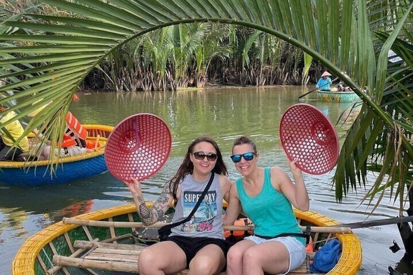 Two people in a boat with red baskets, surrounded by palm trees and water. 5