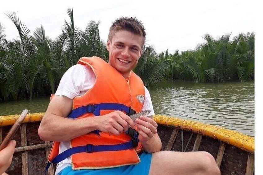 A person in a boat wearing an orange life jacket, holding a fish. 3