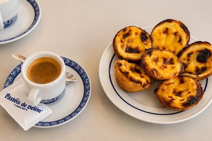 Un plato de Pastéis de Nata y una taza de café sobre una mesa. 2