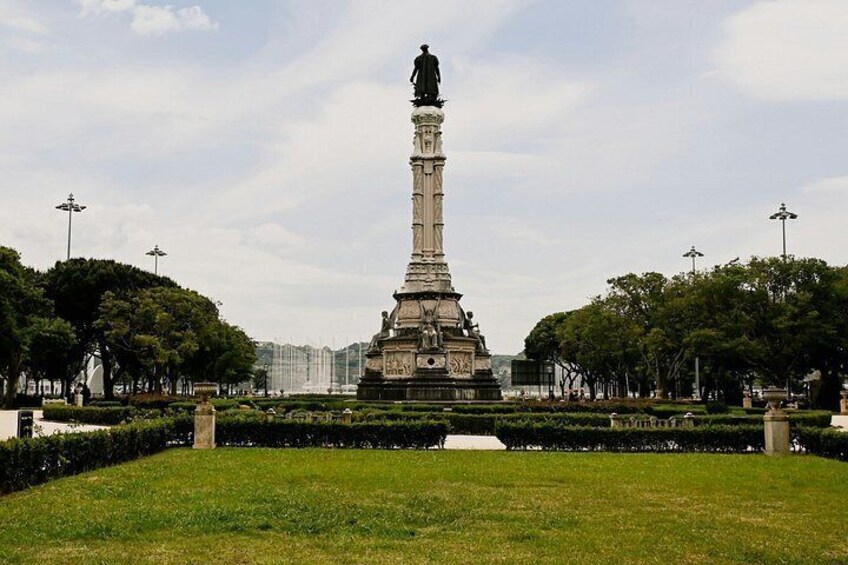 Un monumento alto en un parque con setos y árboles cuidados. 4