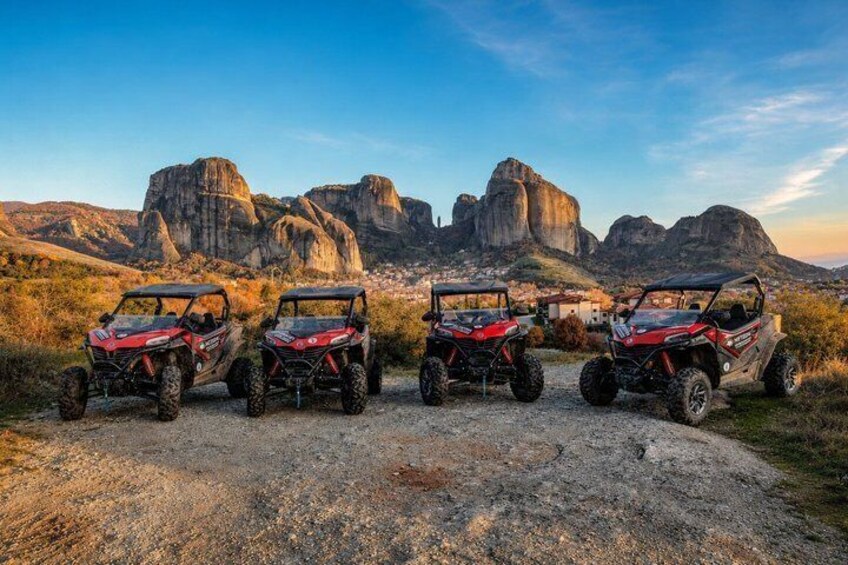 Three off-road vehicles parked on a gravel path with a mountainous landscape in the background. 2