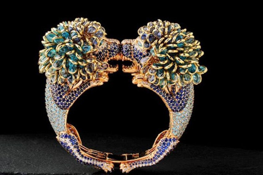 Een gouden speld met blauwe juwelen en een bloemistisch ontwerp. 3