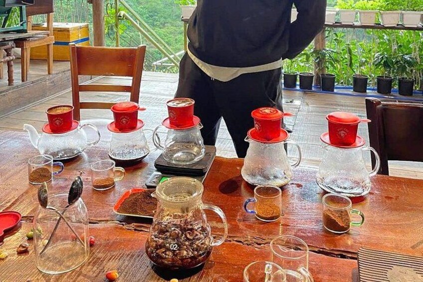 Et bord med forskellige teporter og kopper, en kande og en skål med kaffebønner. 2
