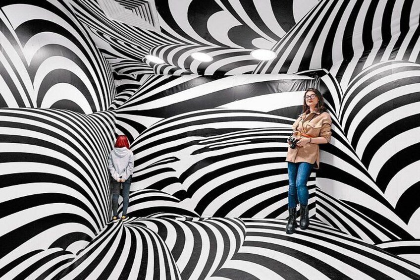 A person standing in a room with a black and white striped pattern on the walls. 4