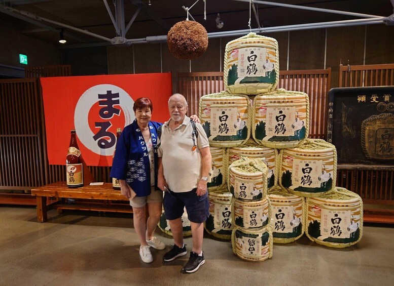 Un homme et une femme se tiennent devant une exposition de barils de saké japonais traditionnels. 1