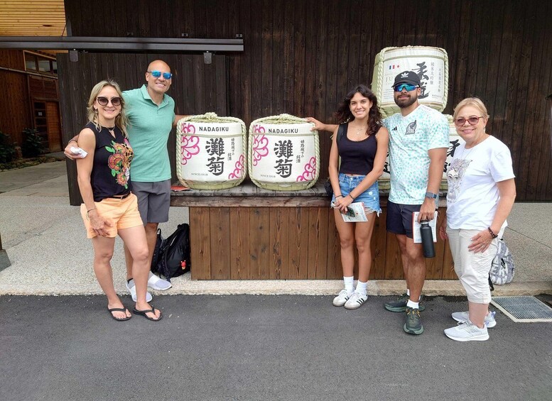 Un groupe de personnes se tient devant une structure en bois, à côté de grands sacs étiquetés « NADAGIKU » et « SINCE1910 ». 4