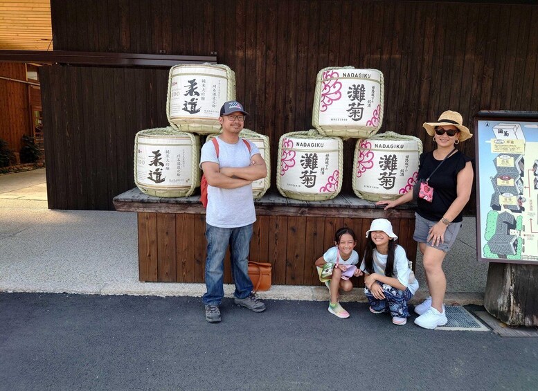 Un homme et deux enfants se tiennent devant de grands sacs sur lesquels figurent des inscriptions en japonais. On aperçoit en arrière-plan une structure en bois et une carte. 5