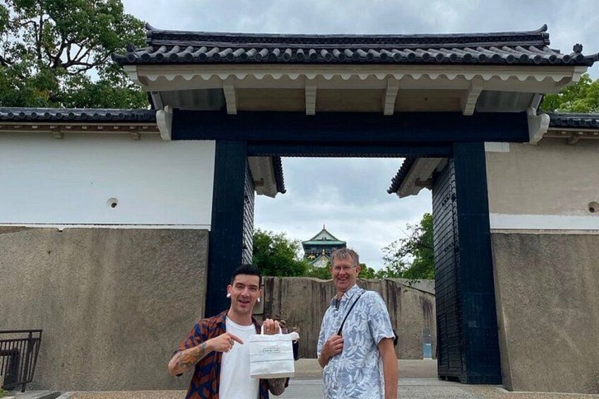 Due persone in piedi sotto un cancello tradizionale giapponese, con in mano un certificato. 3