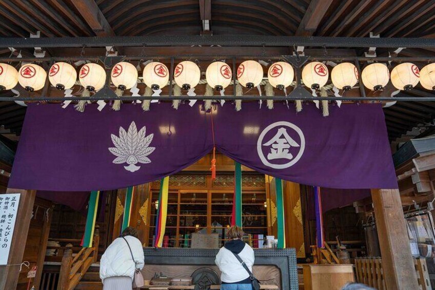 Un edificio japonés tradicional con un estandarte morado, linternas y estructuras de madera. 1