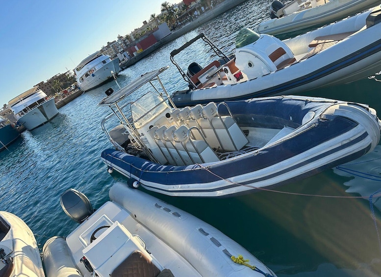Un port de plaisance où sont amarrés plusieurs bateaux, dont un canot pneumatique bleu équipé de sièges et d’un moteur. 3