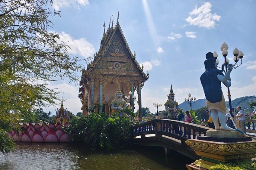 Ein traditioneller thailändischer Tempel mit aufwendiger Architektur, einem Lotus-Teich und einer Brücke. 3