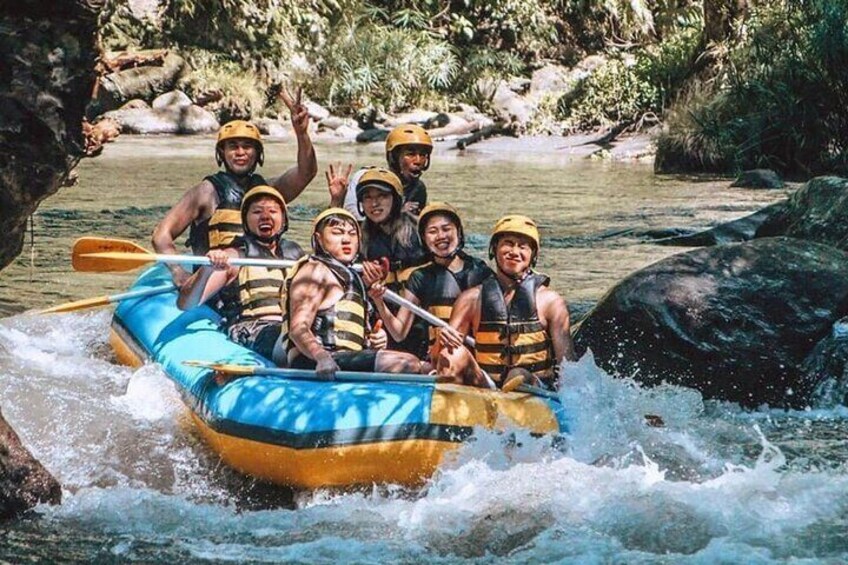 A group of people in a blue raft navigating a river with rapids. 1