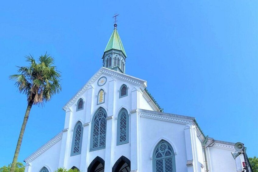 A white church with a green spire and arched windows. 1