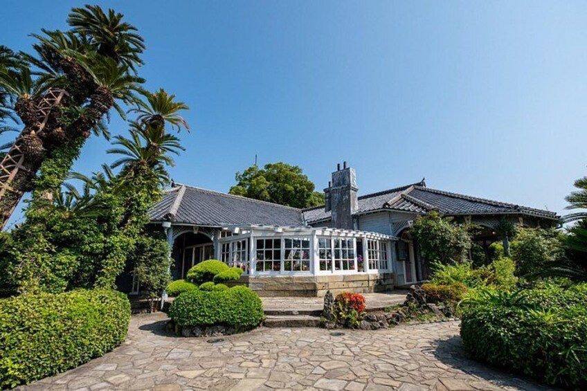 A traditional house with a tiled roof, surrounded by lush greenery and a stone pathway. 4