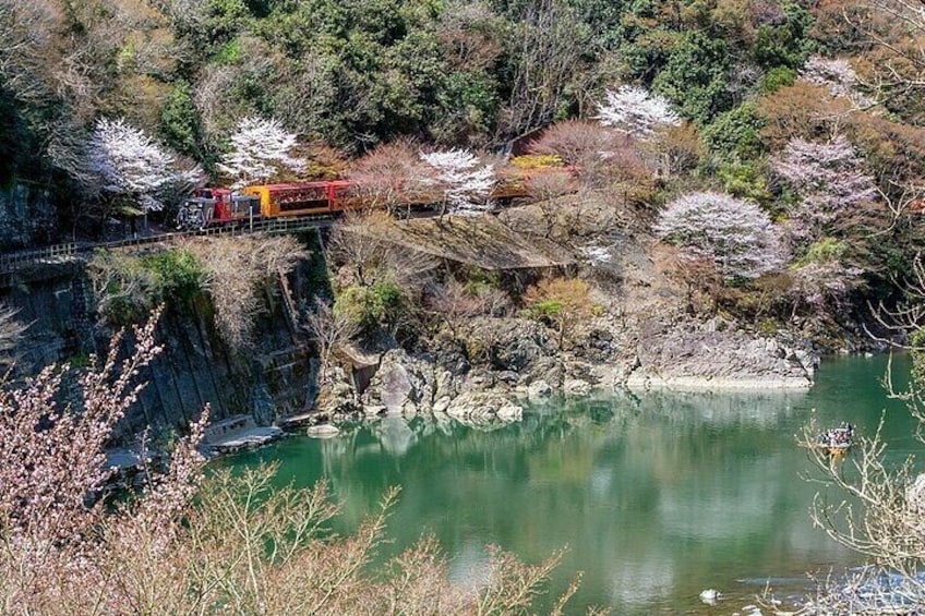 A train on a bridge over a calm river, surrounded by trees and rocky terrain. 5