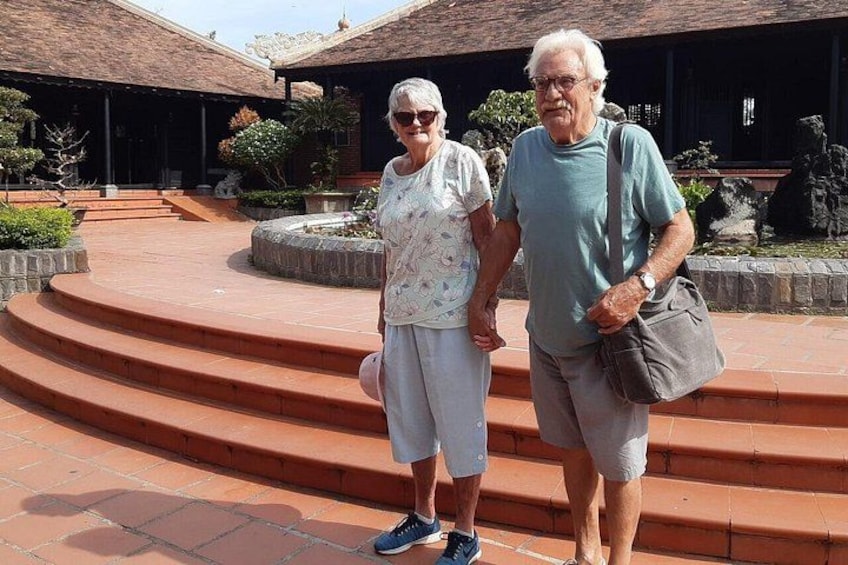 Two people standing on a curved brick pathway with a building and garden in the background. 5