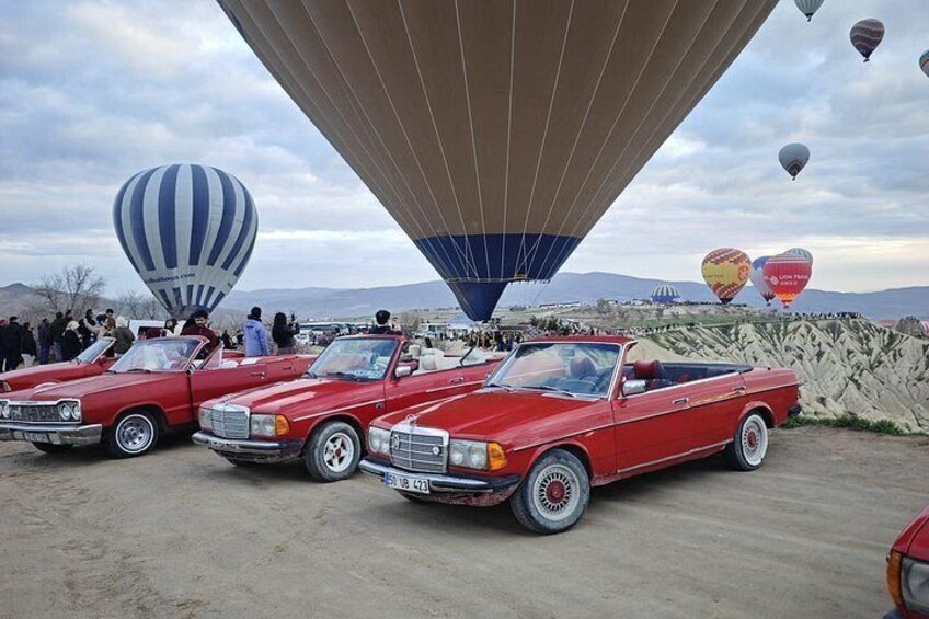 Vintage red cars parked under a hot air balloon. 2