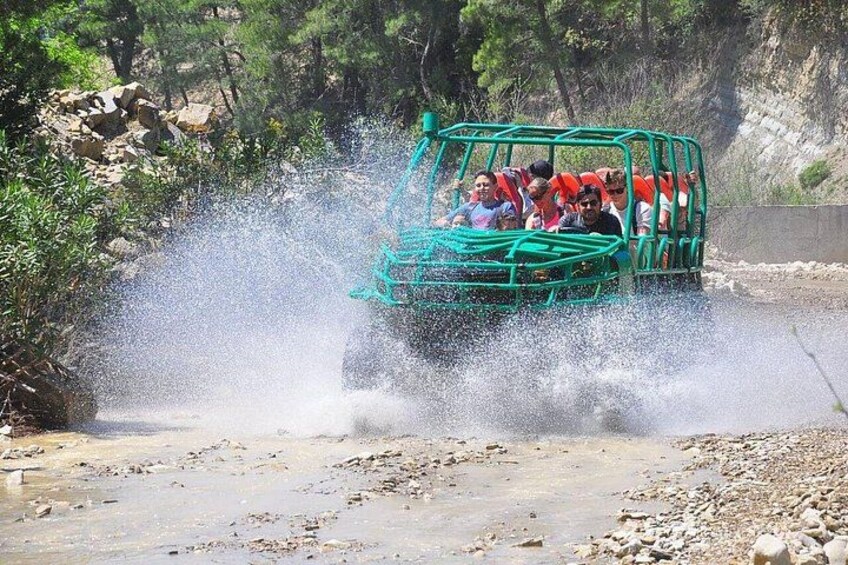 A green vehicle driving through a shallow water body, creating a splash. 1